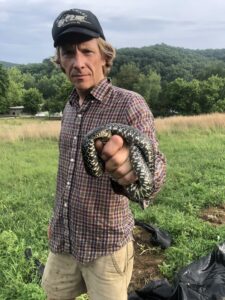 Sculptor Matt Weir with a snake on Little Farm